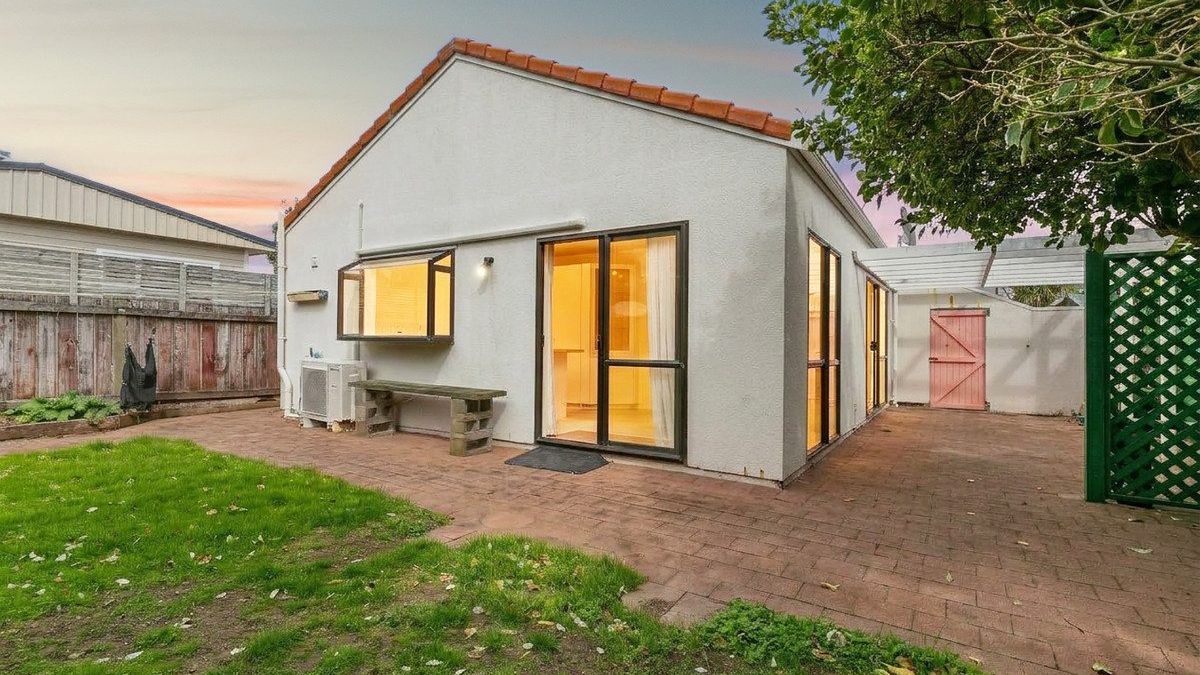 Cross-lease house in Auckland with a paved courtyard and shared fence line